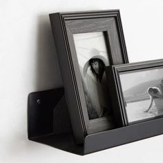 two framed pictures are sitting on a shelf next to a black and white photo frame