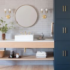 a bathroom with two sinks, mirrors and blue cabinetry on the wall above it