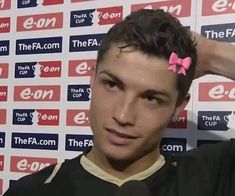 a man with a pink bow on his head in front of a red and white wall