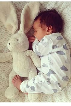 a baby sleeping next to a stuffed animal