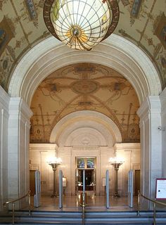 the inside of a building with stairs leading up to an entry door and stained glass dome