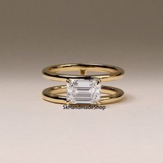 two gold rings with an emerald cut diamond