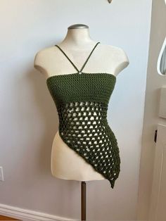 a white mannequin wearing a green crocheted tank top with an open back