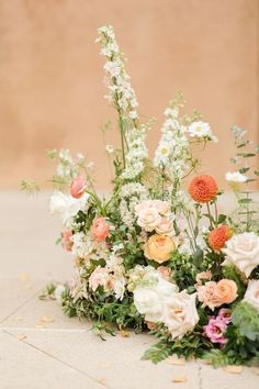 an arrangement of flowers and greenery on the ground