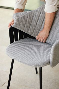 a man sitting on top of a chair with his hand on the back of it