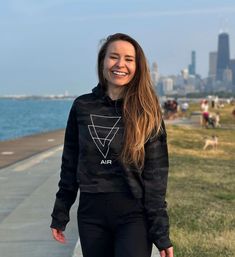 a young woman is walking down the sidewalk by the water