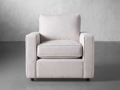 a white chair sitting in front of a gray wall with a light colored back and arms