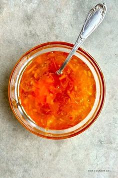 a glass bowl filled with soup on top of a white counter next to a spoon