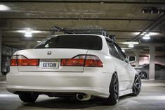 the back end of a white car with a rack on it's roof in a parking garage