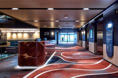 an empty lobby with marble counter tops and red carpeted flooring on either side