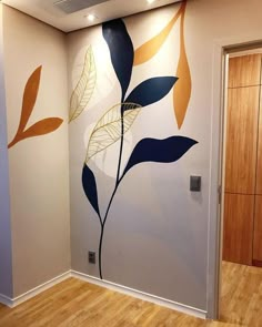 an empty room with painted leaves on the wall and wood flooring in front of it