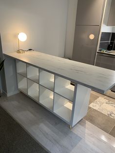 a white counter top sitting inside of a kitchen next to a light on the wall