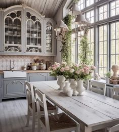 a dining room table with vases and flowers on it in front of a window