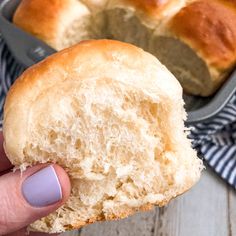 a person holding a piece of bread in their left hand with the rest of the loaf behind them