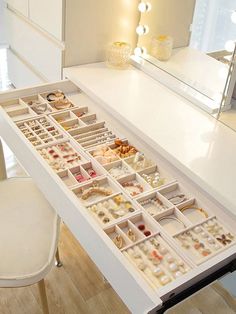 a white table with lots of jewelry on it and a mirror in the back ground