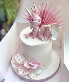 a white cake with pink frosting and an animal figurine sitting on top