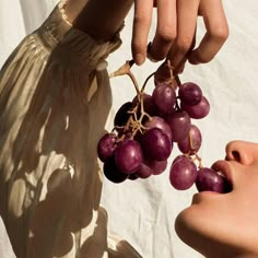 a person holding grapes up to their face