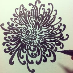 someone is drawing a flower with black ink