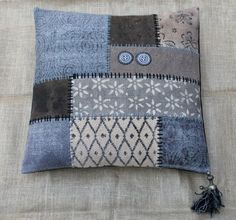 a decorative cushion made with patchwork and tassels on a linen pillow cover