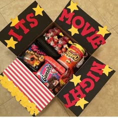 an open box filled with candy and candies on top of a tile floor next to a sign that says it's movie night