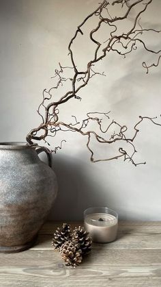 a vase sitting on top of a wooden table next to a candle and a pine cone