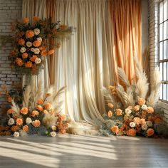 an orange and white floral arrangement in front of a brick wall with sheer drapes