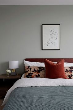 a bed with two pillows and a painting on the wall