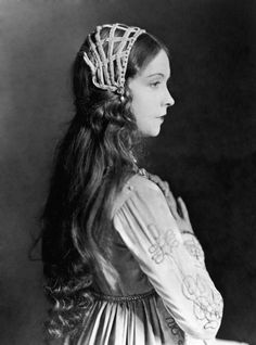 an old photo of a woman with long hair wearing a tiara and green dress