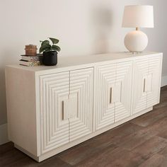 a white cabinet with two doors and a lamp next to it on top of a hard wood floor