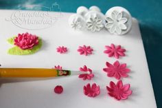 a cake decorated with fondant flowers, leaves and a crayon pencil being used to decorate the icing