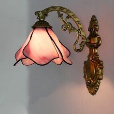 a wall light with a pink glass shade on it's arm and back end