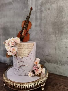 there is a violin on top of the cake and it has pink flowers around it