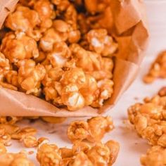 a bag full of caramel popcorn sitting on top of a white tablecloth next to some pieces of paper