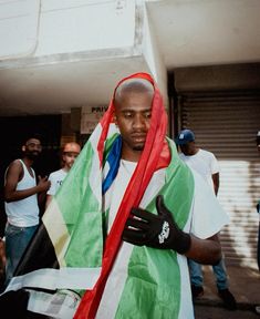 a man in a green, white and red scarf is holding his hand over his shoulder