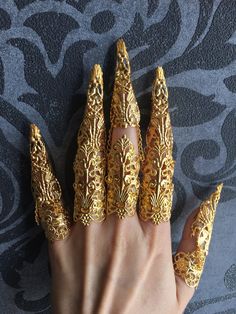 CONTENT: Finger armor rings made of gold colored metal pieces. The two-hand set has 10 full finger armors with claws, 6 are made up of three joints (for the index, middle and ring long fingers) and 4 of only two (for the thumb and little finger) to be the most comfortable to wear. Choose your quantity, a single jewel for a finger, by 5 for a complete hand or by 10 for both hands! Style 2 is made up of 3 pieces, the two of the base being linked together, the claw alone being separated by chains. The armors are fully adjustable to the wearer by slightly bending the parts that compose them, one size, suitable for all genres and all styles according to your desires. This piece is a best seller in my shop, you can wear it in a costume setting, for a wedding, festival, convention or any event. S Raven Oc, Finger Claws, Claws Nails, Skull Bracelets, Nail Armor, Gold Armor, Genshin Characters, Metal Mask, Double Rings