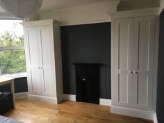 a bedroom with black walls and white cupboards next to a window in the corner