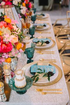 the table is set with colorful flowers and gold chargers for an elegant dinnereon party