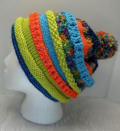 a white mannequin head wearing a multicolored knitted beanie hat