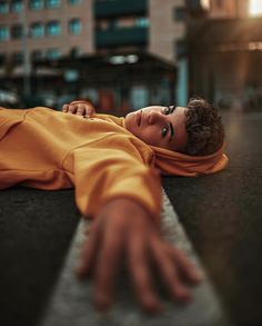 a young man laying on the ground with his hand out to touch him, wearing an orange outfit