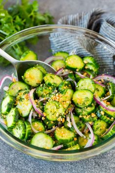 a glass bowl filled with cucumbers and onions