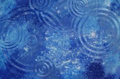 an abstract blue background with swirls and bubbles in the center, as well as water droplets