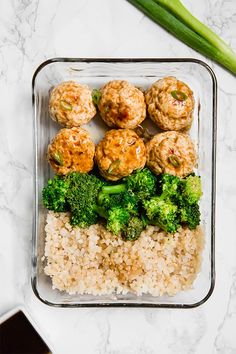 a glass container filled with meatballs and broccoli on top of white rice