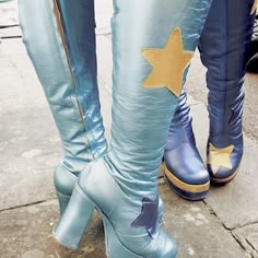 two people wearing blue boots with gold stars on the side and one person's legs