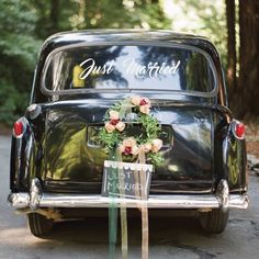 an old black car with flowers tied to it