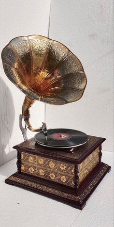 an old fashioned record player sitting on top of a wooden box next to a white wall