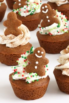 several cupcakes with frosting and decorated gingerbread men on top are shown