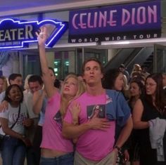 people are standing in front of a theater sign and some have their arms around each other