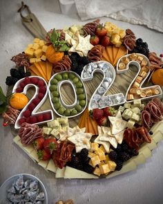 a platter filled with lots of different types of cheeses and fruits in the shape of numbers