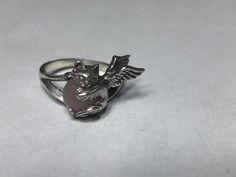 Angel Cat Ring. This cute ring is a sterling silver Angel Kitten with an 8 mm Rose Quartz gemstone.  The Kitty measures 3/4 of an inch (18 mm) across the face and is firmly mounted on a thick shank.  A brand new design;  handmade and hand finished in my studio. The ring pictured is size 8. I will honor any size request up to US size 13 (22.3 mm) same price. The beautiful Brazilian Rose Quartz stone is solidly secured by the paws of this adorable cat. The two wings fit closely to the finger for a safe and comfortable fit.  Also shown with Black Onyx and Carnelian and additionally available with Hematite, Tiger Eye and Opalite.  Please message me with exact size during checkout and stone choice if other than Rose. Sustainable gift box always included.  Thank you for visiting. Black Cat Ring, Spiky Ring, Weird Rings, Angel Rings, Angel Kitten, Cat Rings, Unique Silver Rings, Cute Ring, Angel Cat