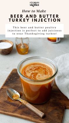 a glass jar filled with liquid sitting on top of a wooden cutting board next to a spoon